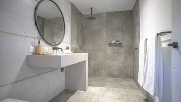Een moderne badkamer met een grote spiegel, een douche en een toilet.