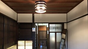 Ein traditionelles japanisches Interieur mit Schiebetüren, Tatami-Böden und einer hängenden Leuchte.