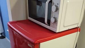 A compact kitchenette with a red refrigerator, a microwave, and a small sink.