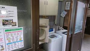 A laundry room with a washing machine, dryer, and a cabinet above. There are signs on the wall with instructions.