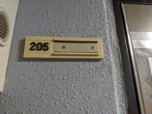 Ein beiges Briefschlitz mit der Nummer 205 in einer strukturierten Wand.