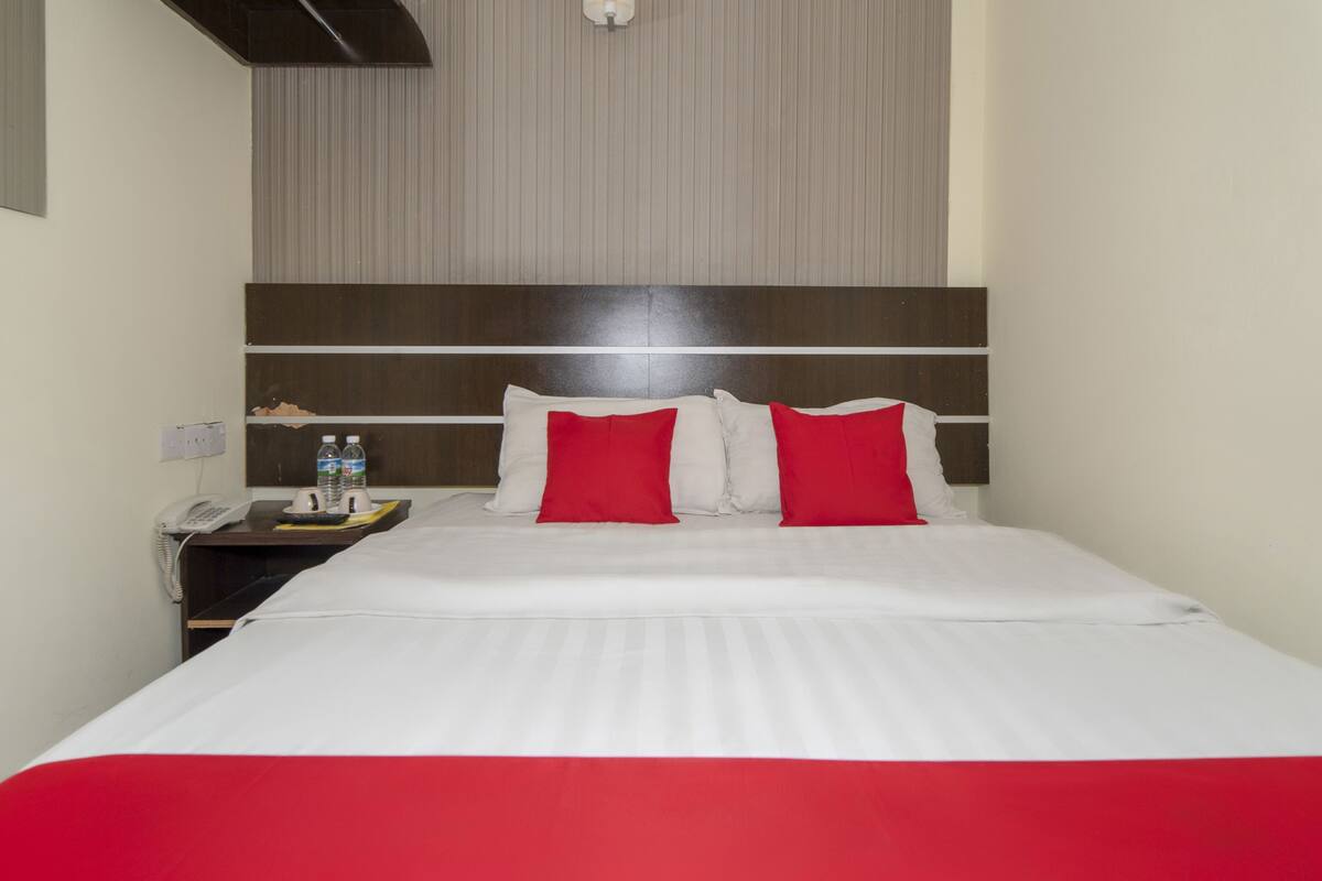 A hotel room with a bed, a nightstand, a phone, and a water bottle.