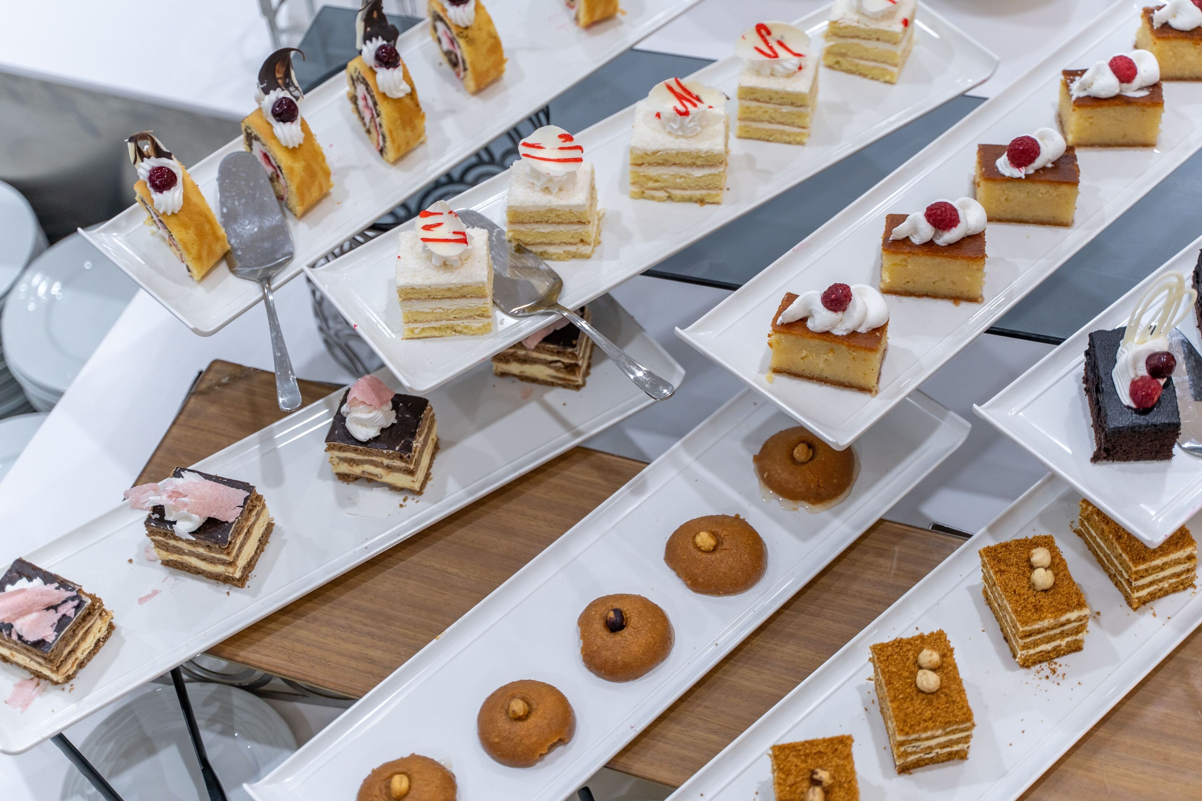 Verschillende desserts gerangschikt op witte, rechthoekige schalen.