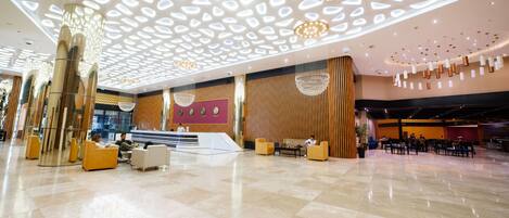 A spacious lobby with a high ceiling, modern chandeliers, and a reception desk.