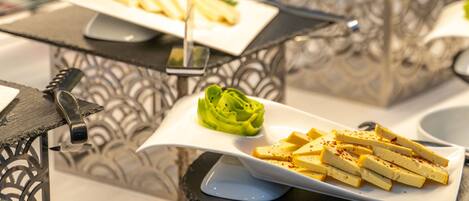 A buffet setup with various dishes, including a plate of fries, a bowl of mushrooms, and a plate of tofu.