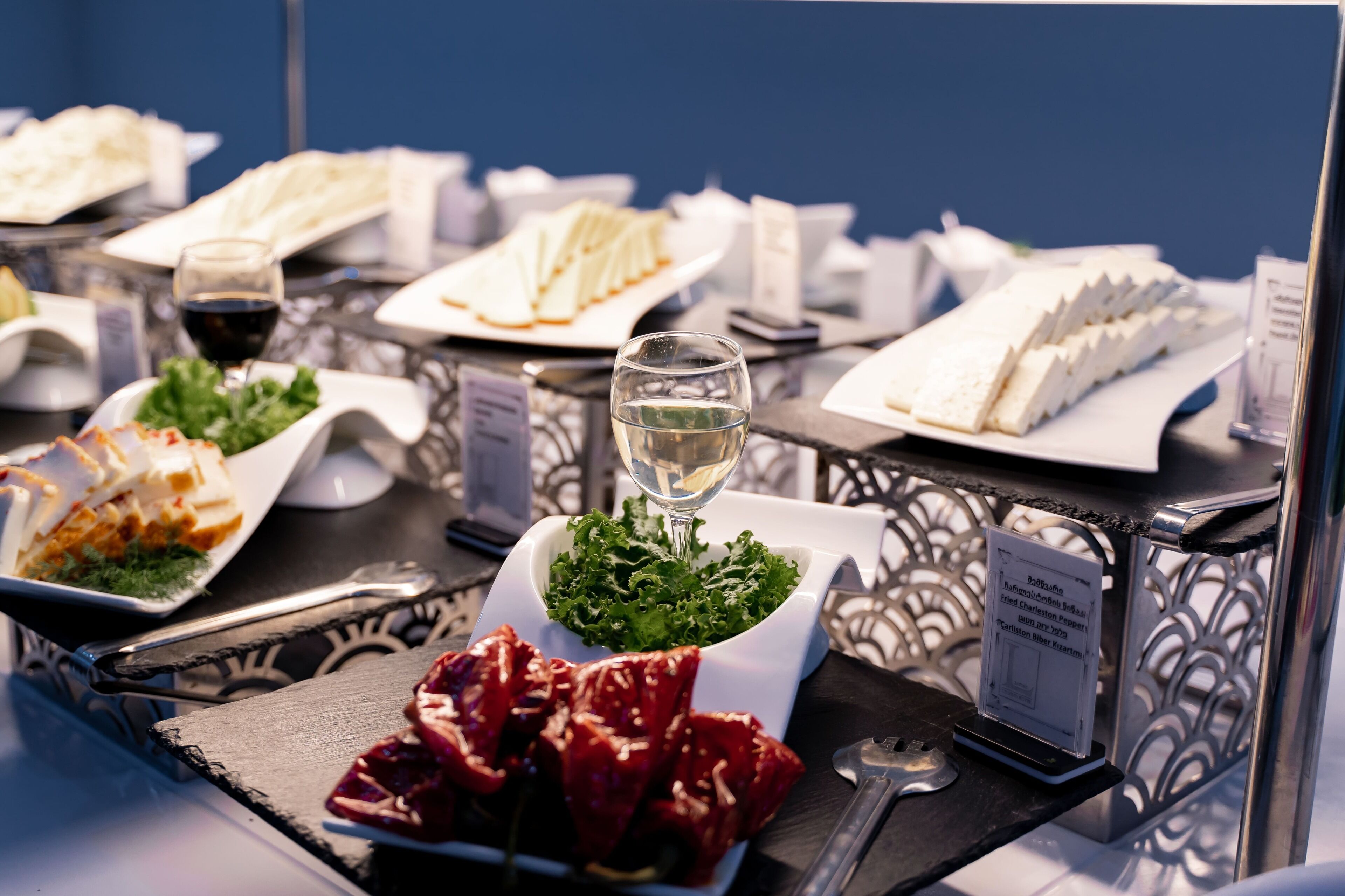 Een buffet met diverse gerechten, een glas witte wijn en een bordje met het broodsoorten.