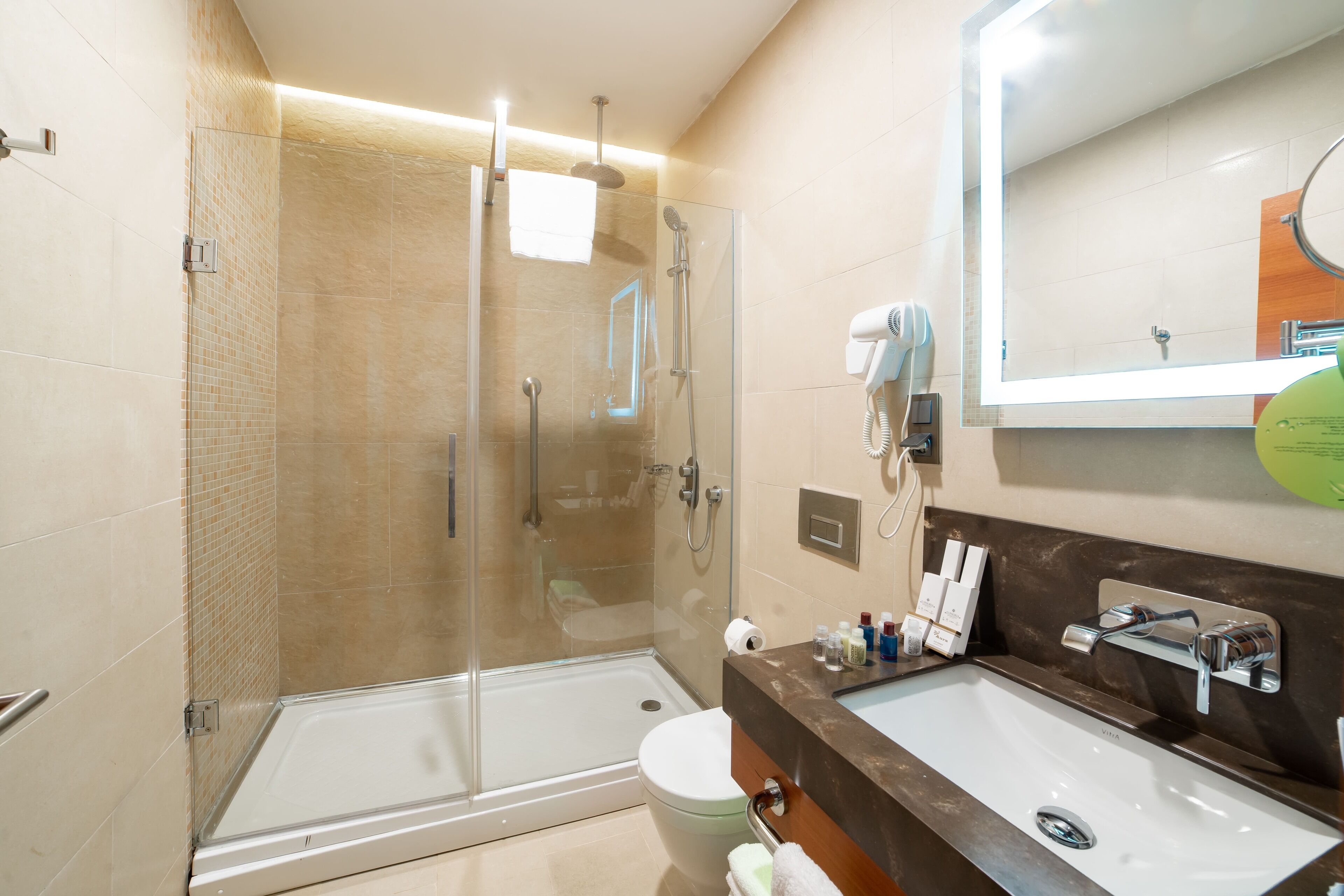 A modern bathroom with a glass shower enclosure, a dual sink vanity, and a large mirror.