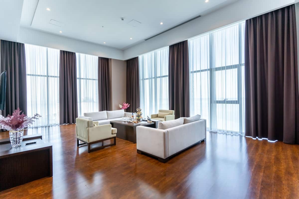A spacious living room with a large sofa set, a coffee table, and a TV on a stand.
