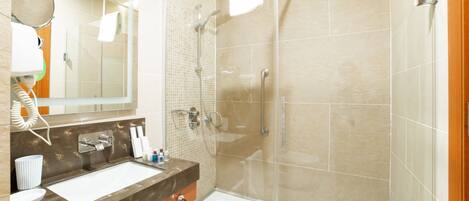 A modern bathroom with a glass-enclosed shower, a vanity with a sink, and a mirror.