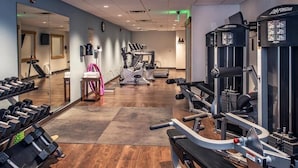 Une salle de sport équipée de machines de cardio, de poids libres et d’un miroir.