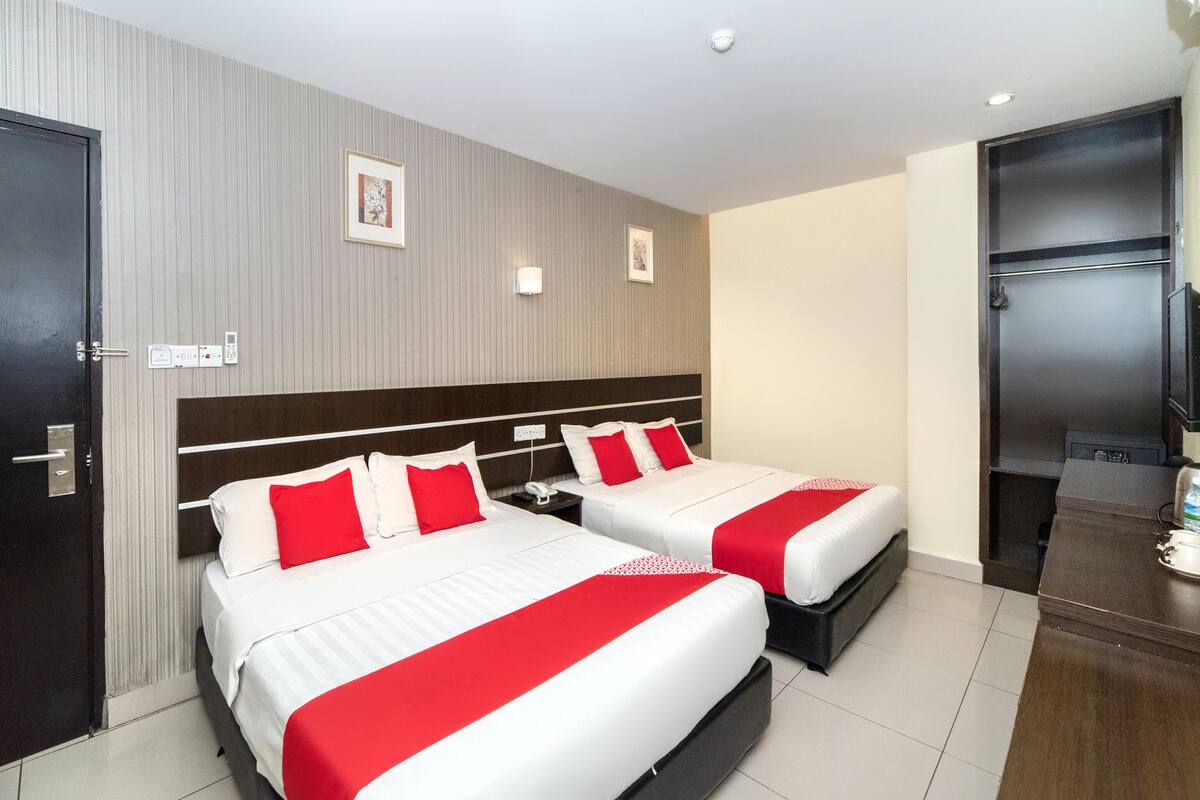 A hotel room with two beds, a minibar, a TV, and a door.