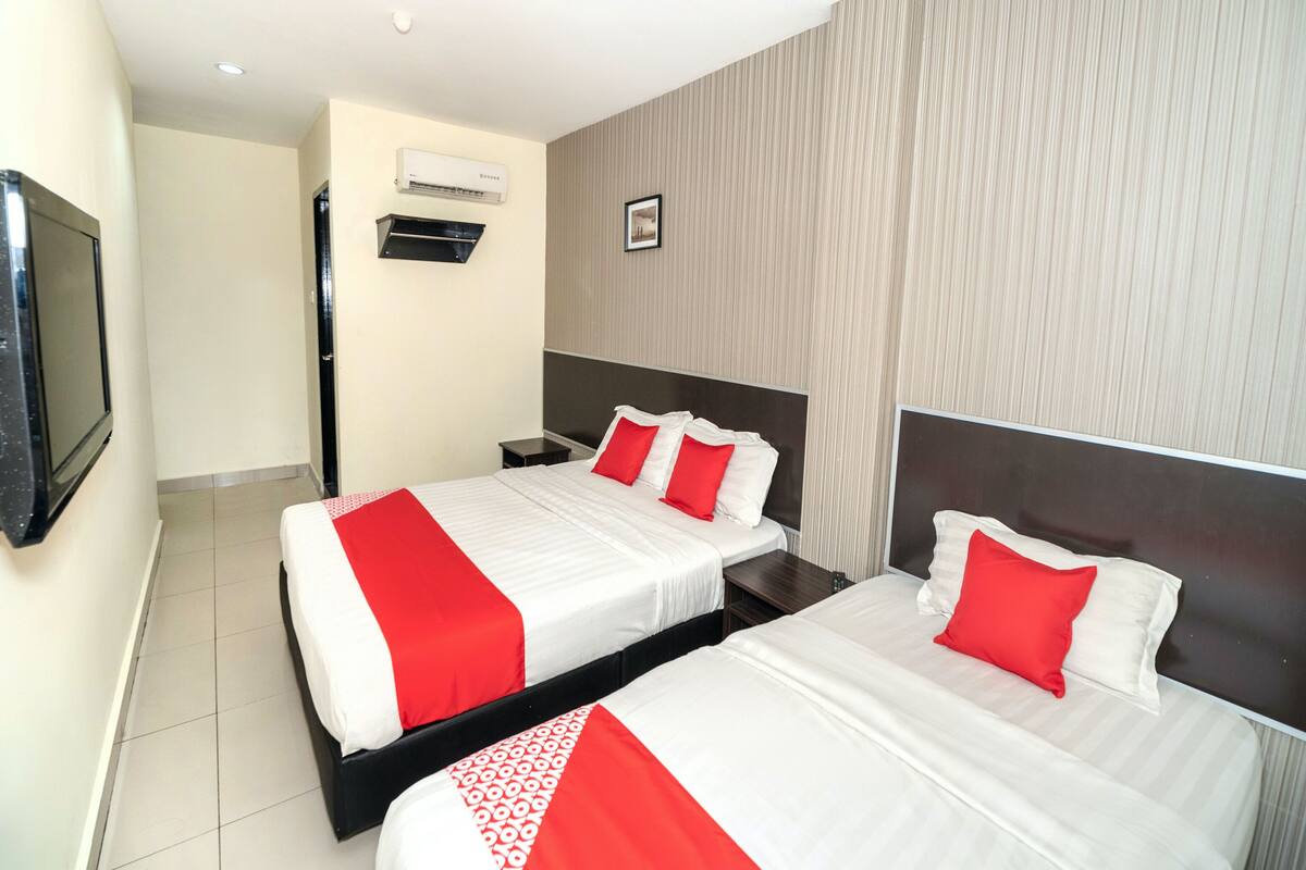 A hotel room with two beds, a flat-screen TV, an air conditioning unit, and a framed picture on the wall.