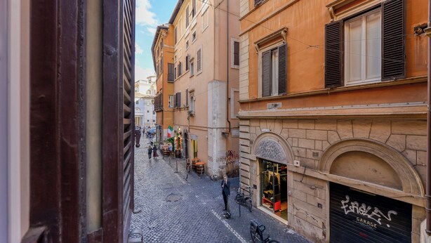 A cobblestone street with buildings featuring arched windows and shutters. - Skylife Spanish Steps Apartment (Roma)