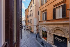 A cobblestone street with buildings featuring arched windows and shutters. - Skylife Spanish Steps Apartment (Roma)