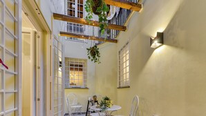 A narrow corridor with a table and chairs, a hanging plant, and a wall-mounted light fixture. - Skylife Spanish Steps Apartment (Roma)