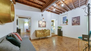 A spacious living area with a herringbone floor, a sofa with cushions, a decorative console table, and artwork on the walls. - Skylife Spanish Steps Apartment (Roma)