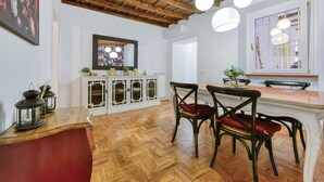 A dining area with wooden flooring, a white cabinet with glass doors, and a dining table with chairs. - Skylife Spanish Steps Apartment (Roma)