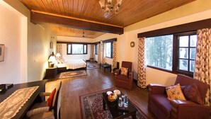 Amplia sala de estar con piso de madera, un ventanal con cortinas, un sofá, una mesa de centro y un comedor con mesa y sillas.