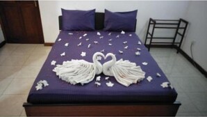 Una cama con una colcha morada, dos almohadas y una decoración de toalla con forma de cisne.