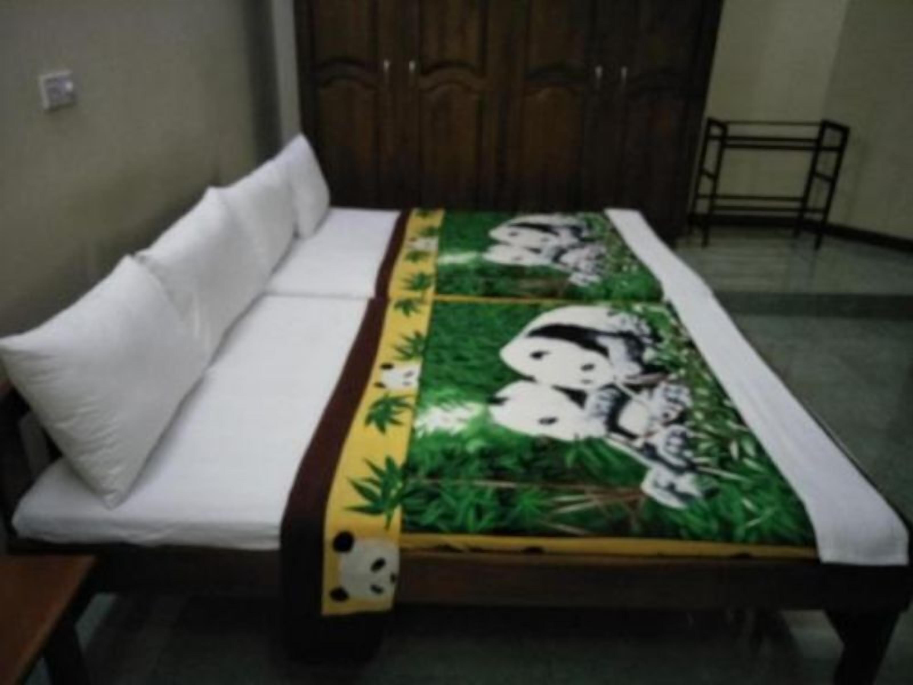 A room with a bed, a wooden wardrobe, and a small table.