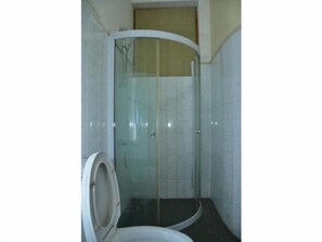 Un baño con cabina de ducha de vidrio, inodoro y paredes de azulejos.