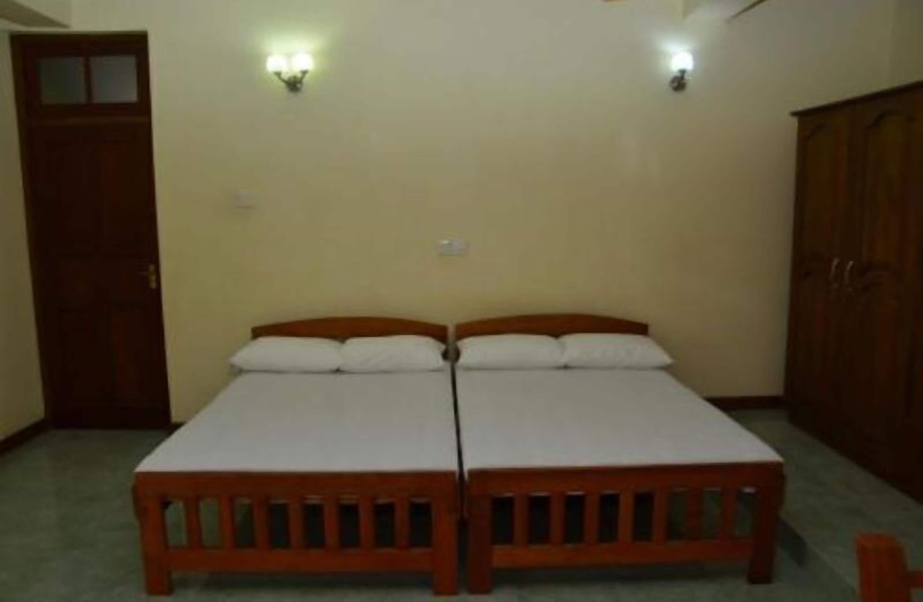Una habitación con dos camas de madera, un armario y luces fijadas a la pared.