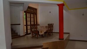 Un comedor con una mesa y sillas, una escalera y un pilar rojo.
