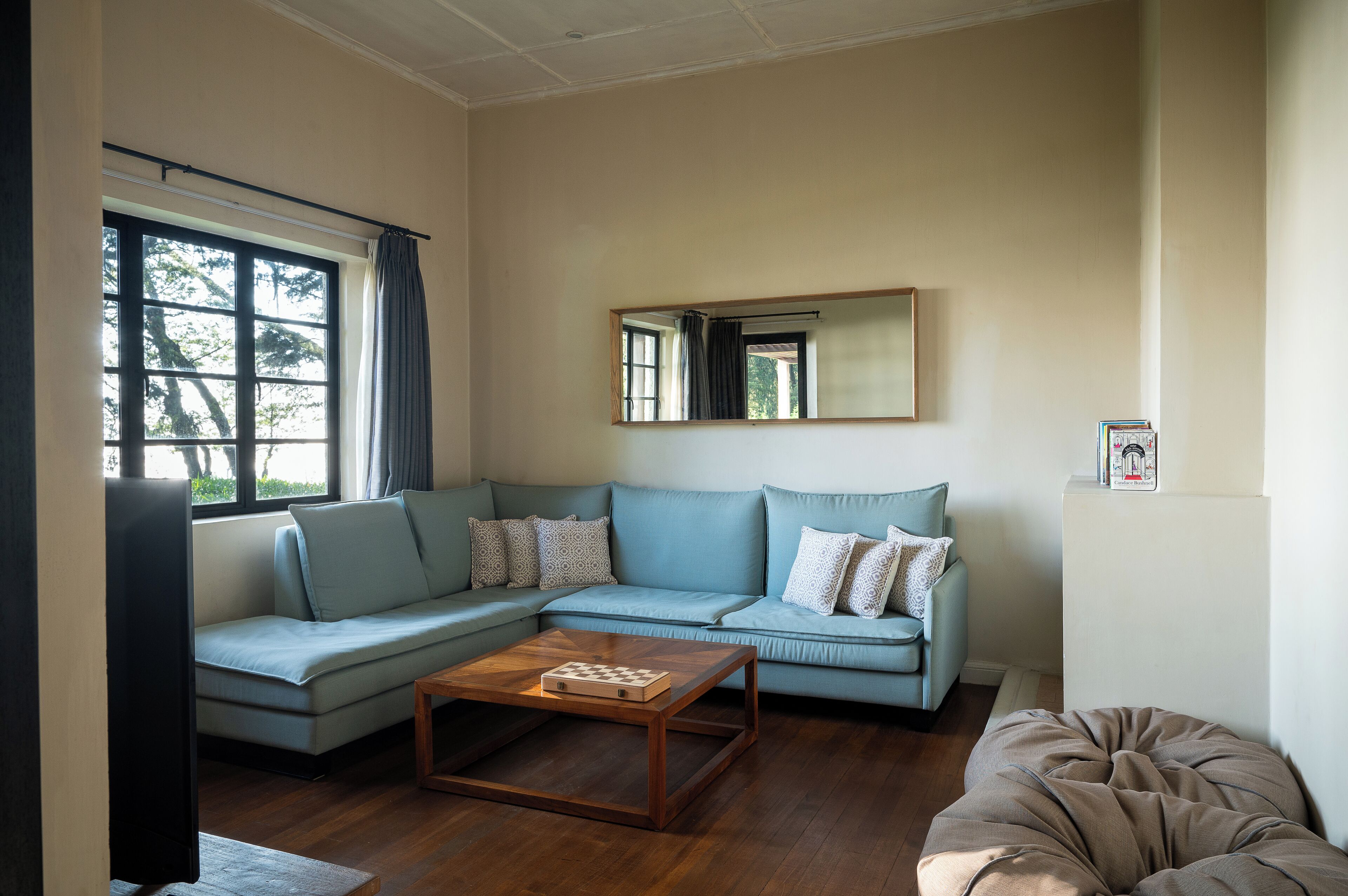 A living room with a light blue sofa, a wooden coffee table, and a beige ottoman.