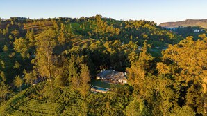 Ein Haus, umgeben von üppiger Vegetation und terrassenförmig angelegten Feldern.