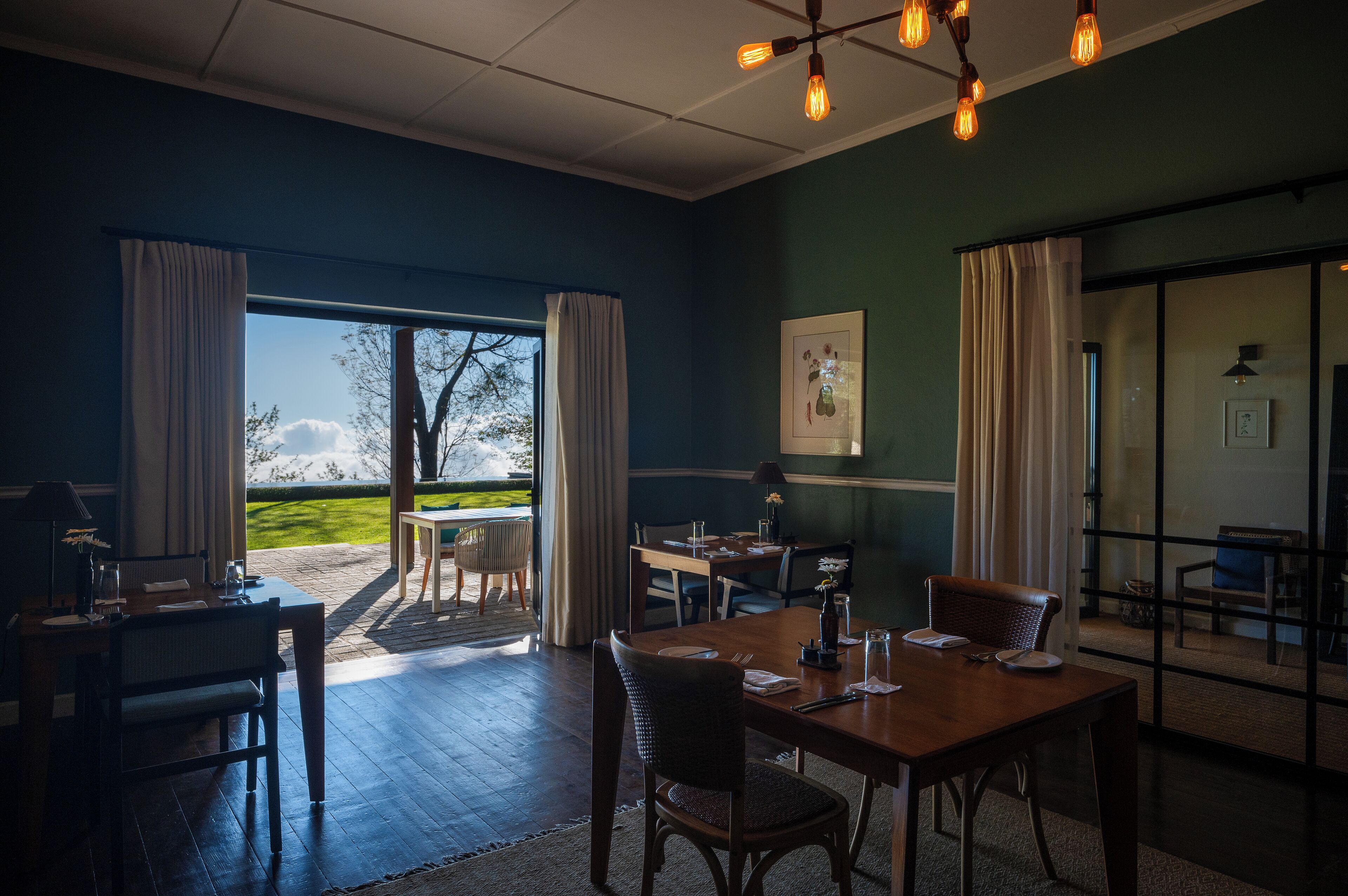 Un espace repas offrant une vue sur un paysage enneigé grâce à de grandes fenêtres, avec des meubles en bois et un lustre.