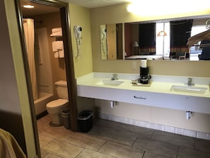 A bathroom with a toilet, two sinks, a mirror, and a coffee machine.