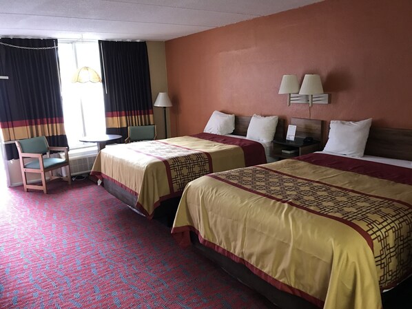 A hotel room with two beds, a desk, a chair, and a window with curtains. - Conner Hill Motor Lodge (Pigeon Forge)
