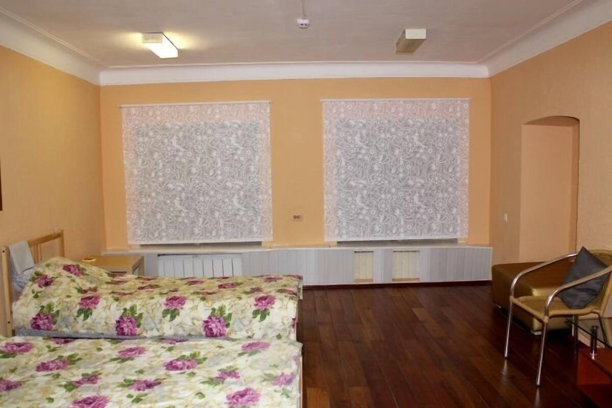 A room with two beds, a chair, and a radiator.
