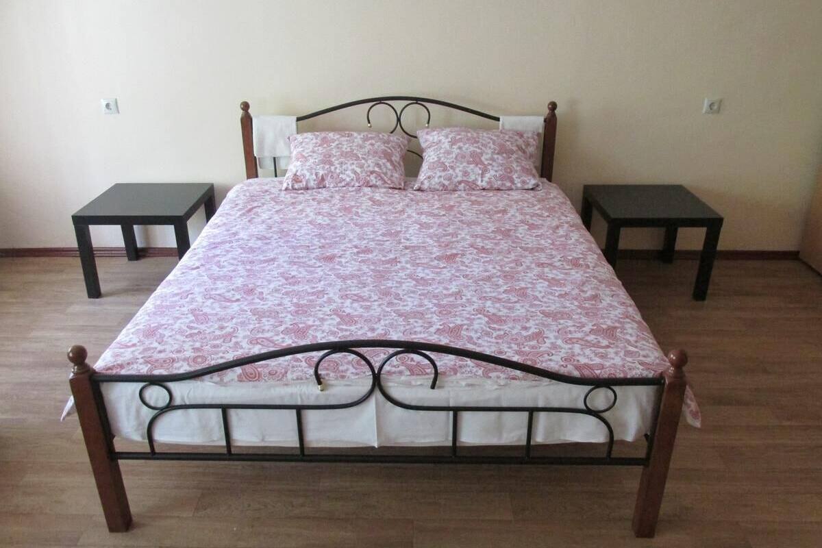 A bed with a metal frame and wooden headboard, flanked by two nightstands.