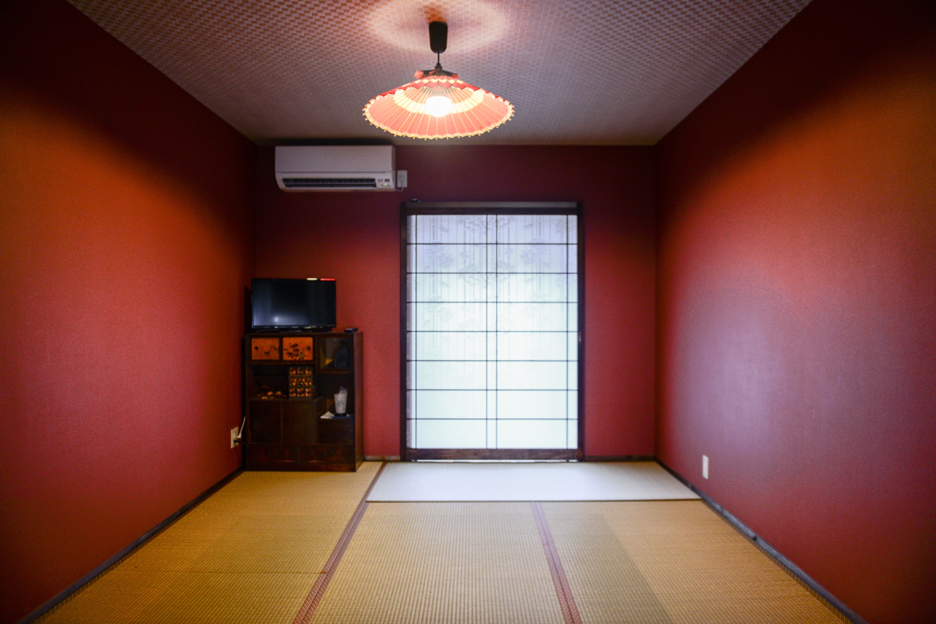Quarto com piso de tatame, porta deslizante e ventilador de teto.