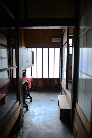 A narrow hallway with wooden walls and a sliding door leading to a room with a large window.