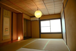 A traditional Japanese room with tatami flooring, a shoji screen, and a hanging paper lantern. - Nishioji Kado (Kyoto)