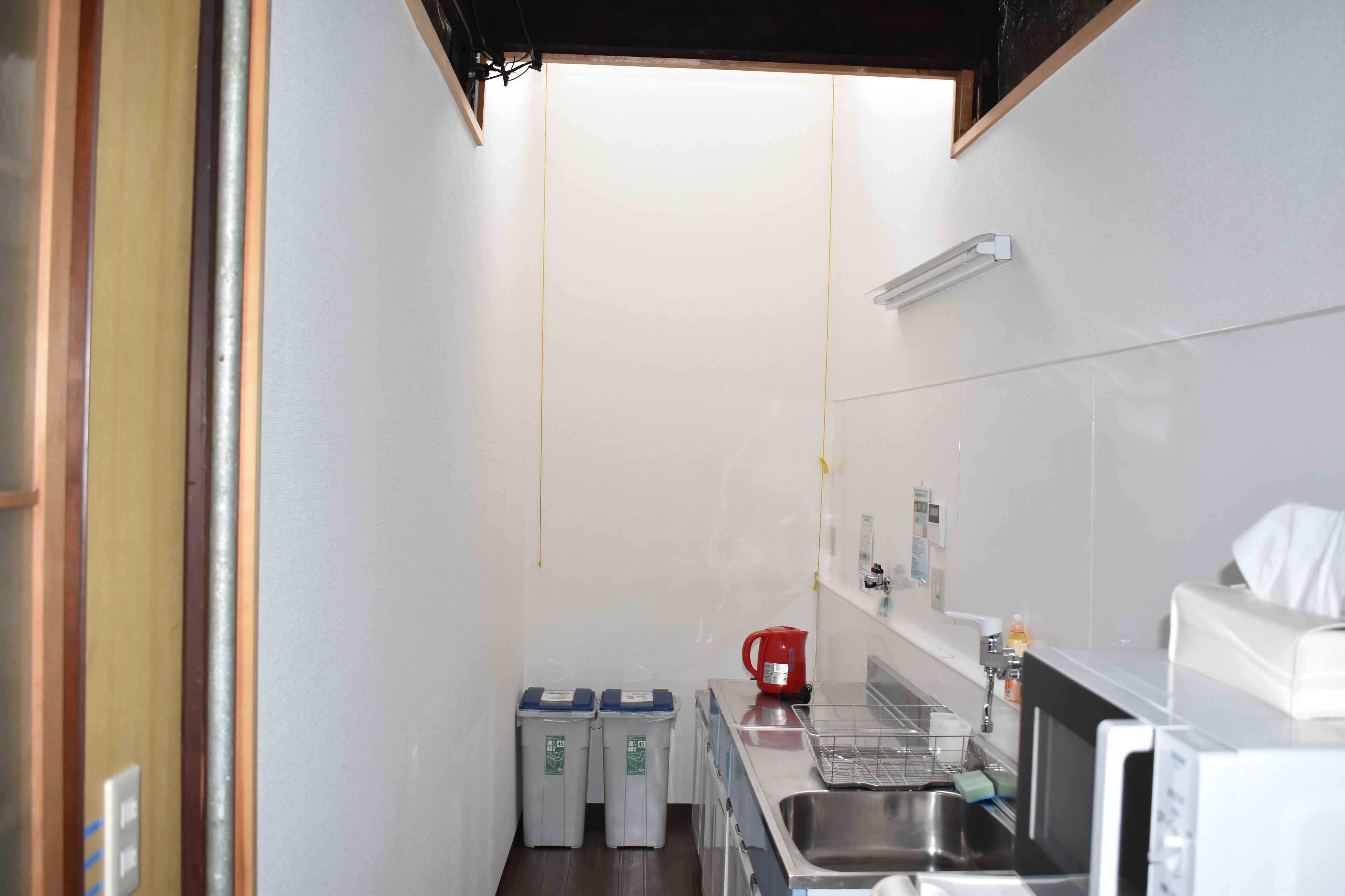 A compact kitchen with a sink, a coffee maker, and two trash bins.