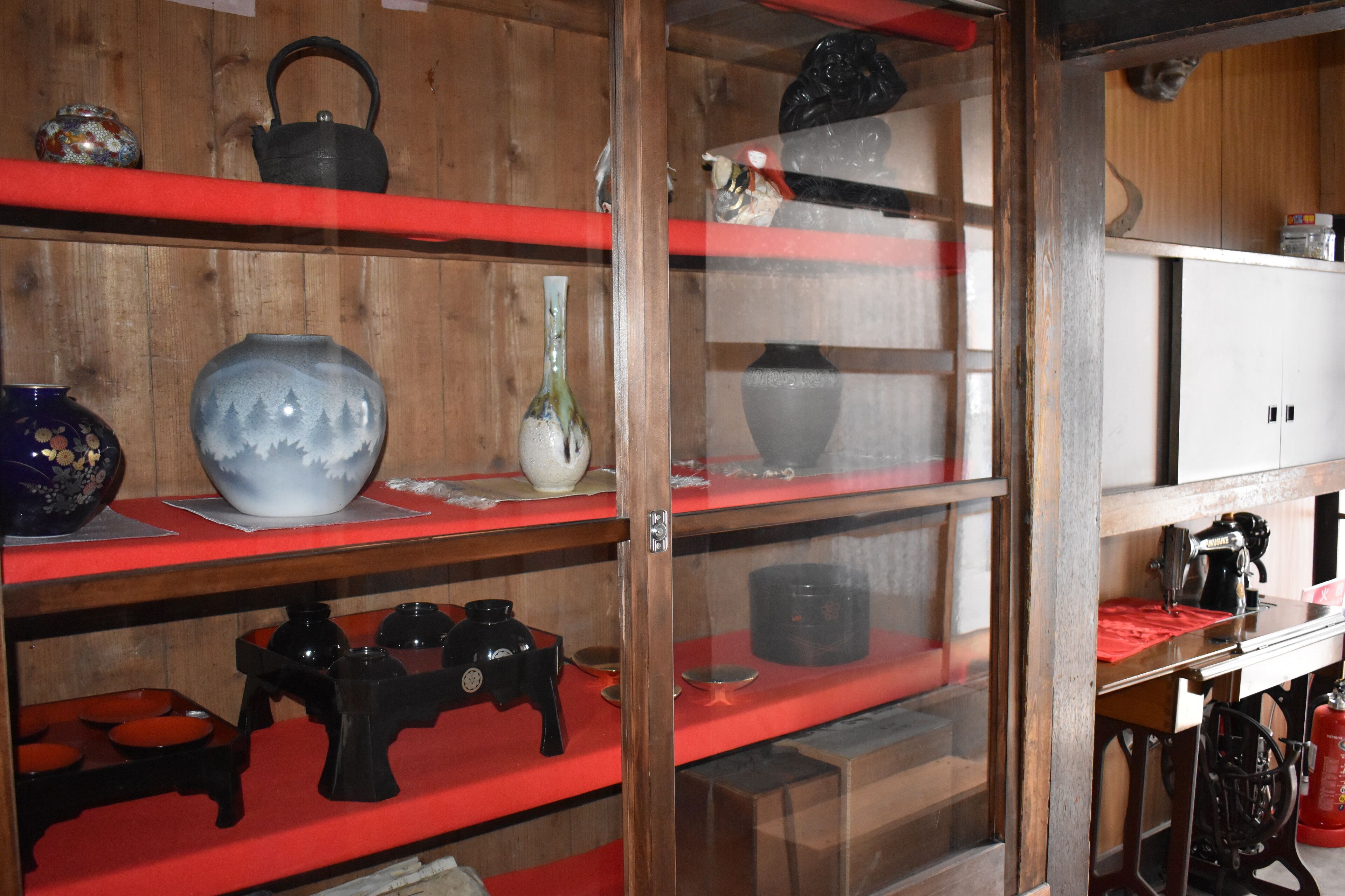 Una habitación con paredes de madera y estantes que muestran diversos objetos de cerámica y utensilios de cocina.