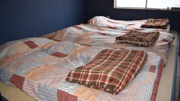 A bed with a patterned quilt and pillows, a window with a view, and a blue wall.