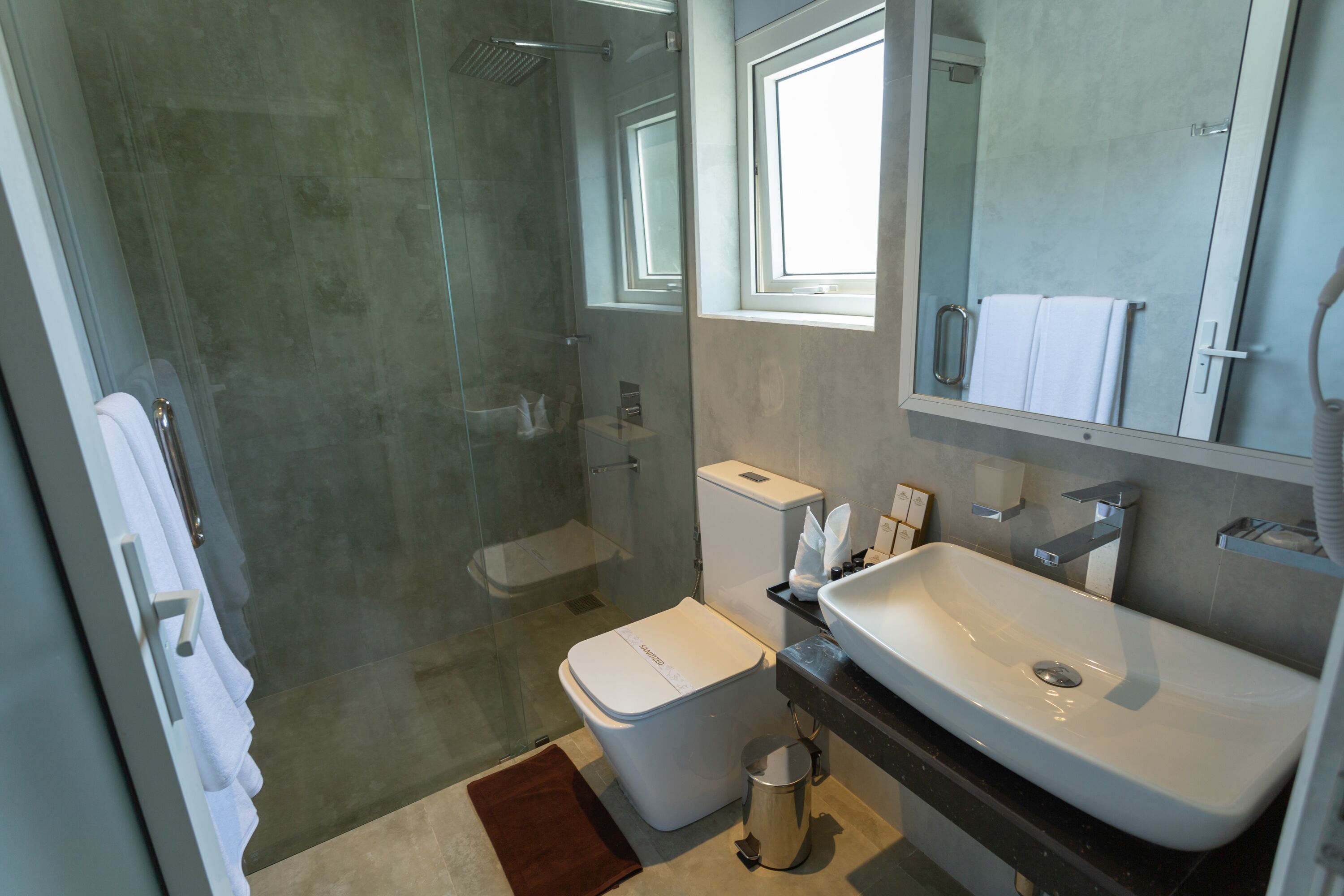 A modern bathroom with a glass-enclosed shower, a white toilet, and a large sink.