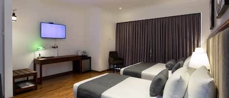 Una habitación de hotel con dos camas, un escritorio, una televisión y una silla.