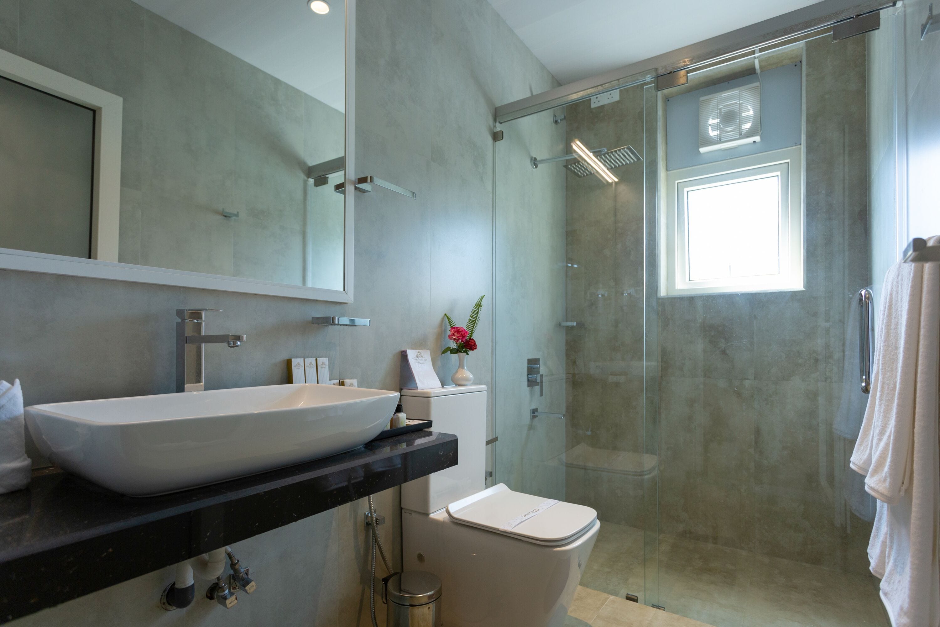 A modern bathroom with a large sink, toilet, and glass-enclosed shower.