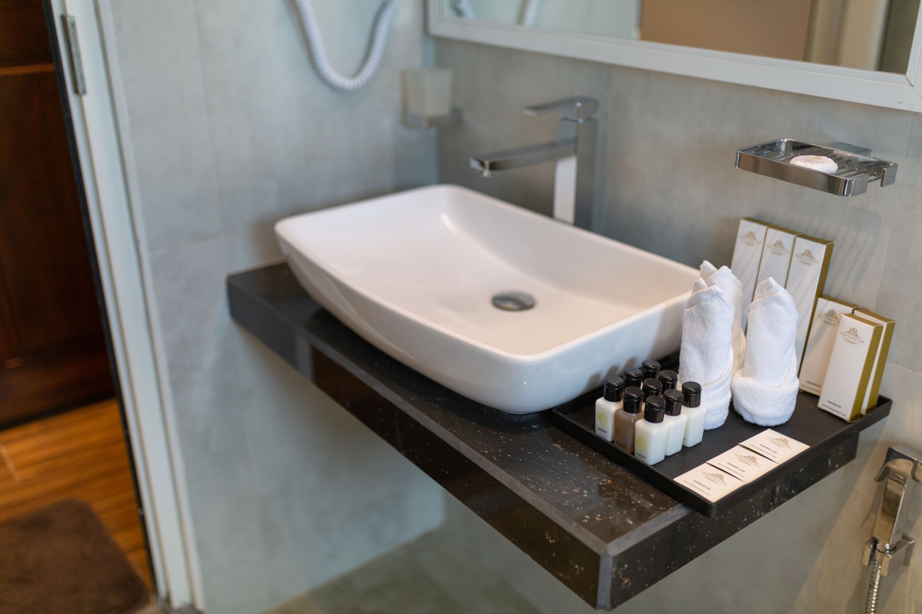 A bathroom with a white sink, a towel rack, and toiletries on a shelf.