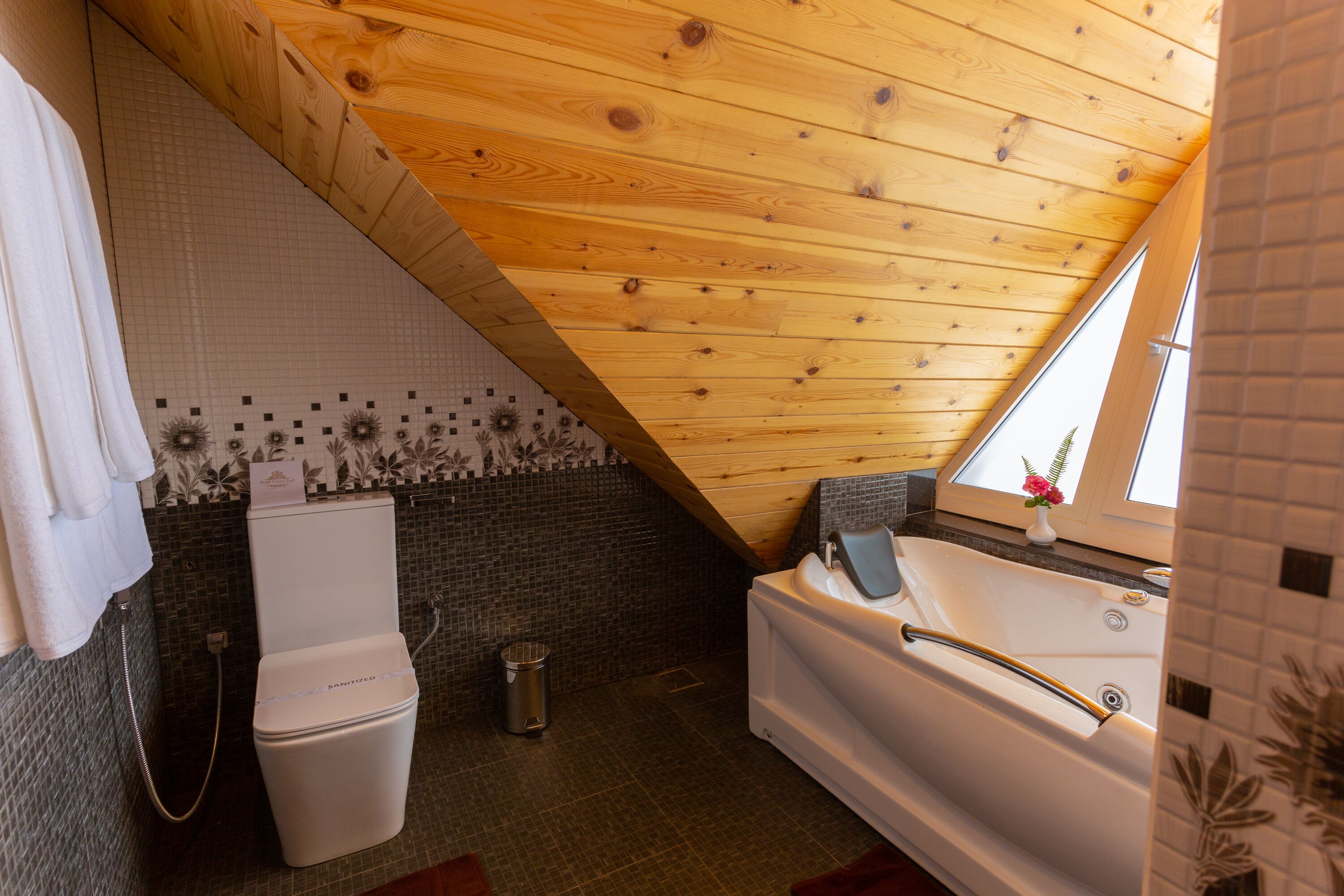 Un baño con techo de madera, bañera, inodoro y ducha.