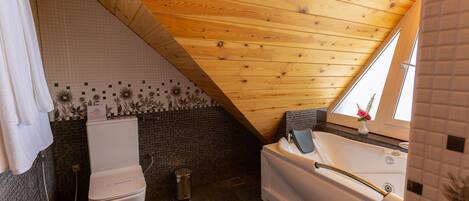 Un baño con techo de madera, bañera, inodoro y ducha.