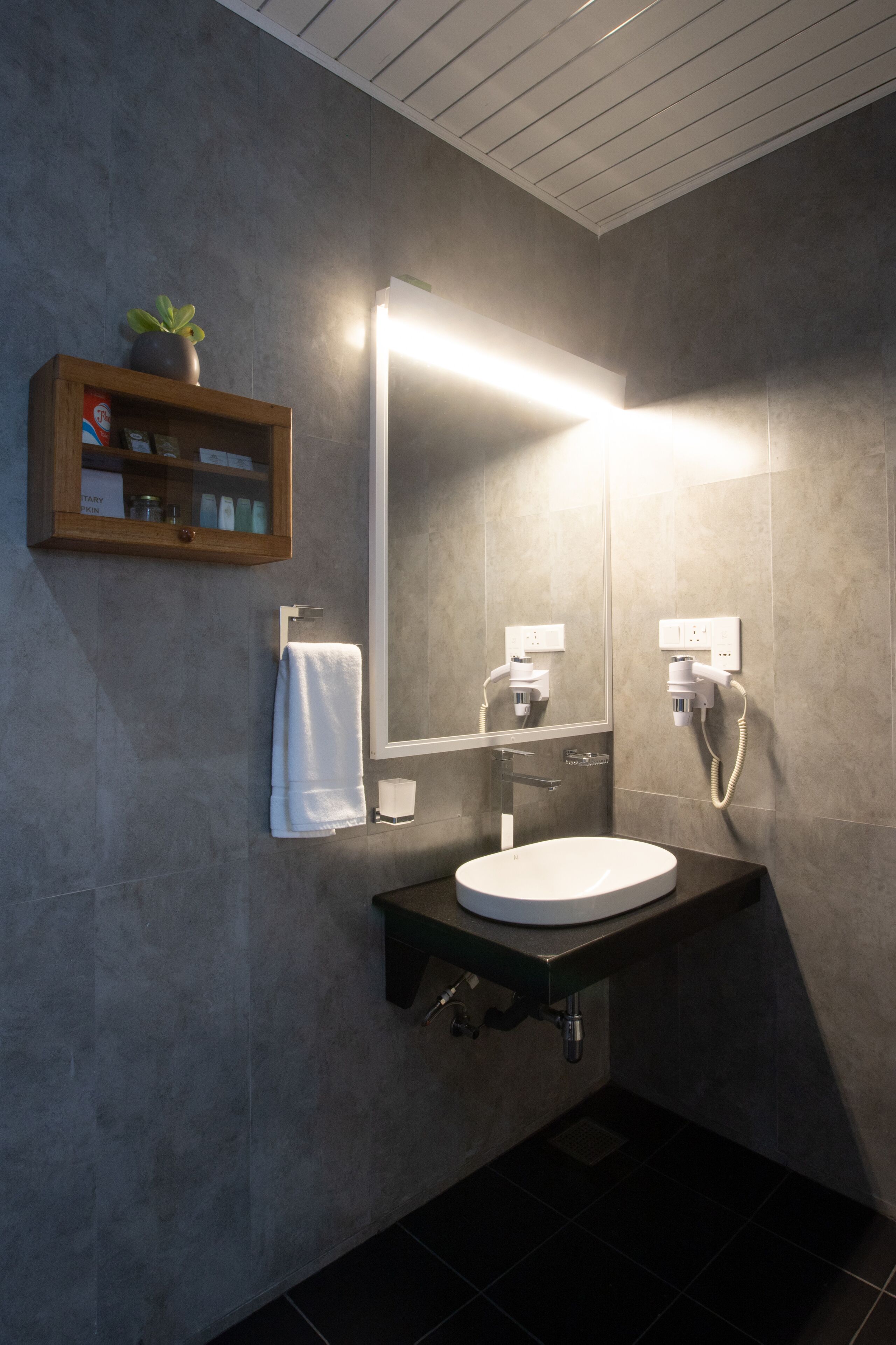 A modern bathroom with a built-in sink, a mirror, and a towel rack.