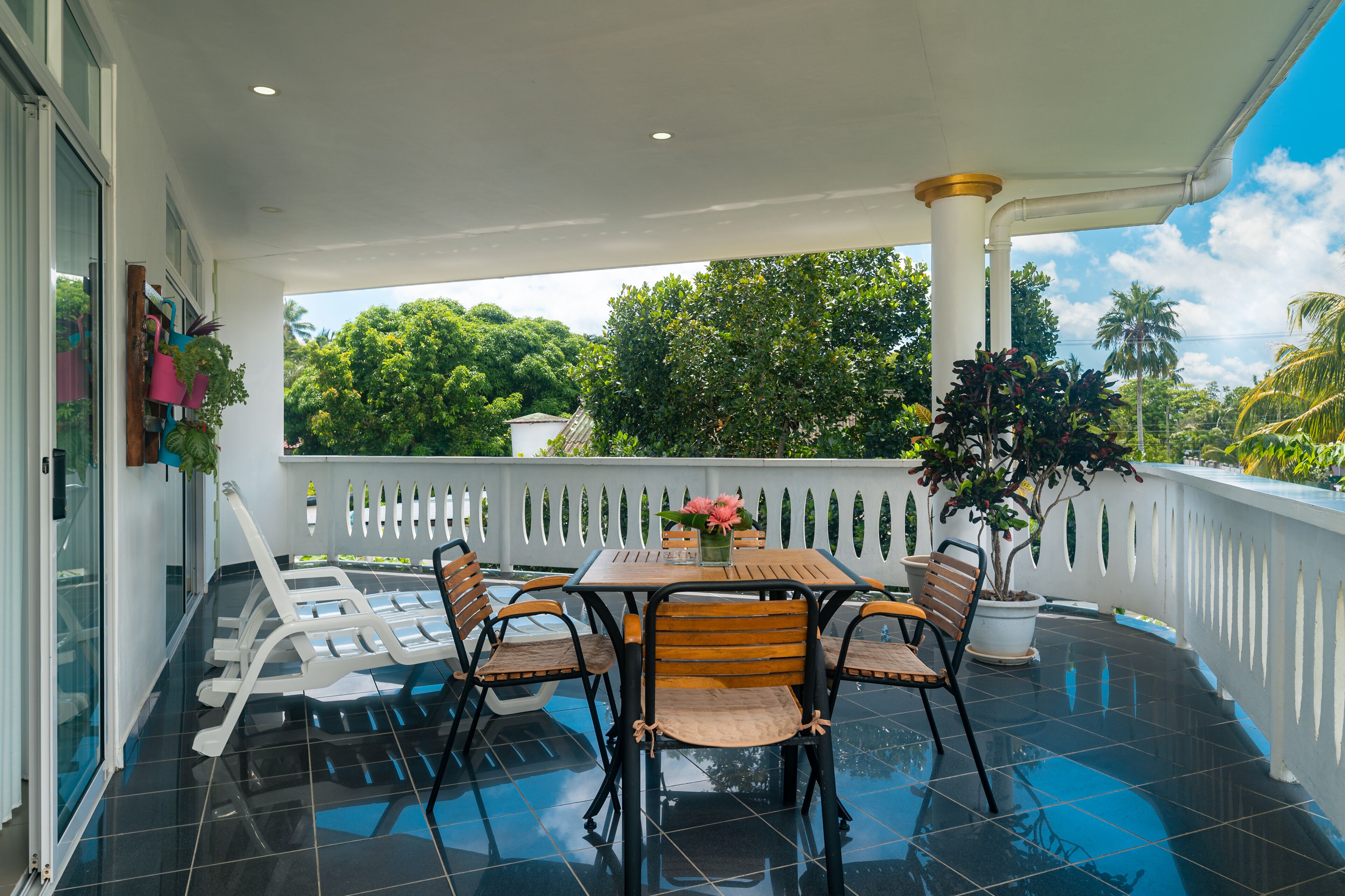 Un espace extérieur abrité, doté d’une table et de chaises, entouré d’une clôture blanche et offrant une vue sur un paysage verdoyant luxuriant.