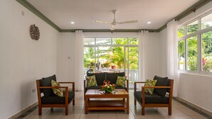 A living room with a sofa, two armchairs, a coffee table, and a ceiling fan. - 340 Mountain View Apartments (Mahé Island)