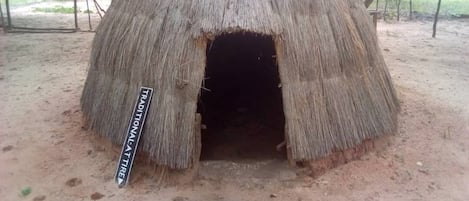 A traditional thatched hut with a sign indicating its cultural significance.